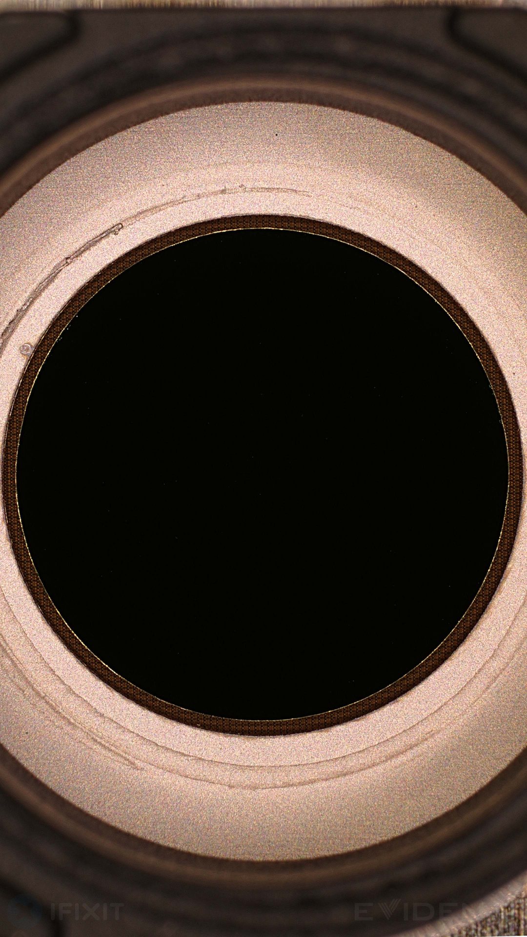 iFixit microscope photo of the IR-pass filter beneath the OLED, appearing as a dark eclipse ring