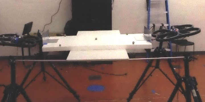 Two quadrotors docked to a foam-core panel in the lab